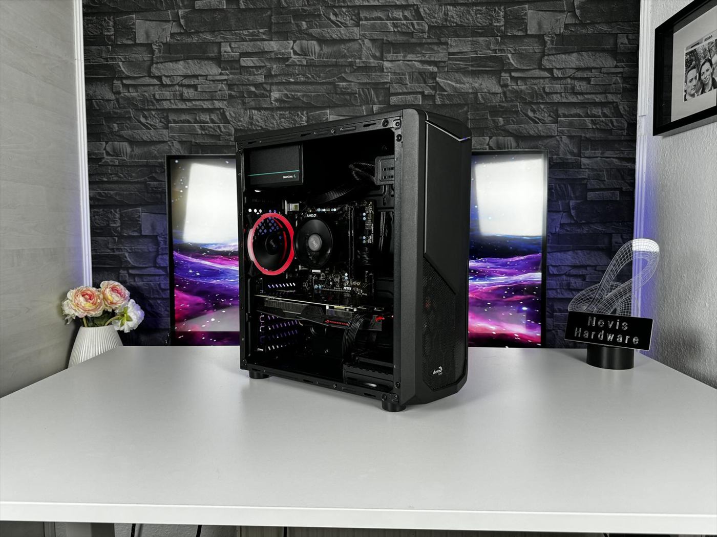 Schwarzer Gaming-PC mit offenem Seitenteil vor zwei Monitoren